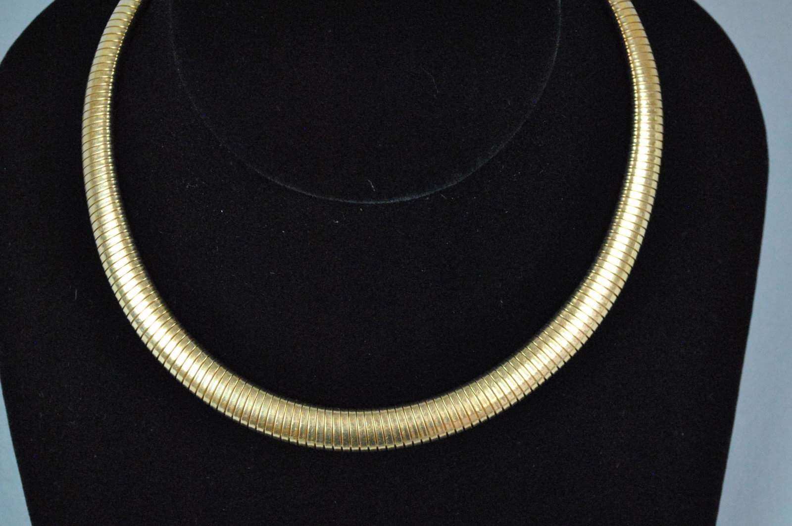 14K OMEGA FLEXIBLE CHOKER, 69.4GMS.: 14K OMEGA FLEXIBLE CHOKER, 69.4GMS. c.1950's, in yellow gold, stamped 'Forstner 14KT', some discoloration at closure area, height 9mm, length 16in., 69.4gms., Opening Bid $1000