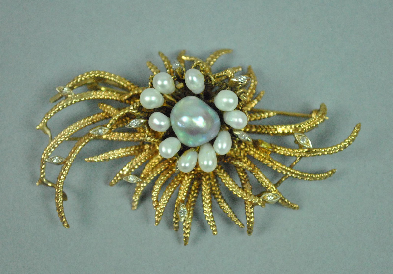14K BAROQUE PEARL & DIAMOND FREE-FORM BROOCH: 14K BAROQUE PEARL & DIAMOND FREE-FORM BROOCH set with a center bluish gray (11mm) pearl, accented with 10 white pear shaped pearls, and 11 diamond melee (one diamond replaced with a yellowish likely g