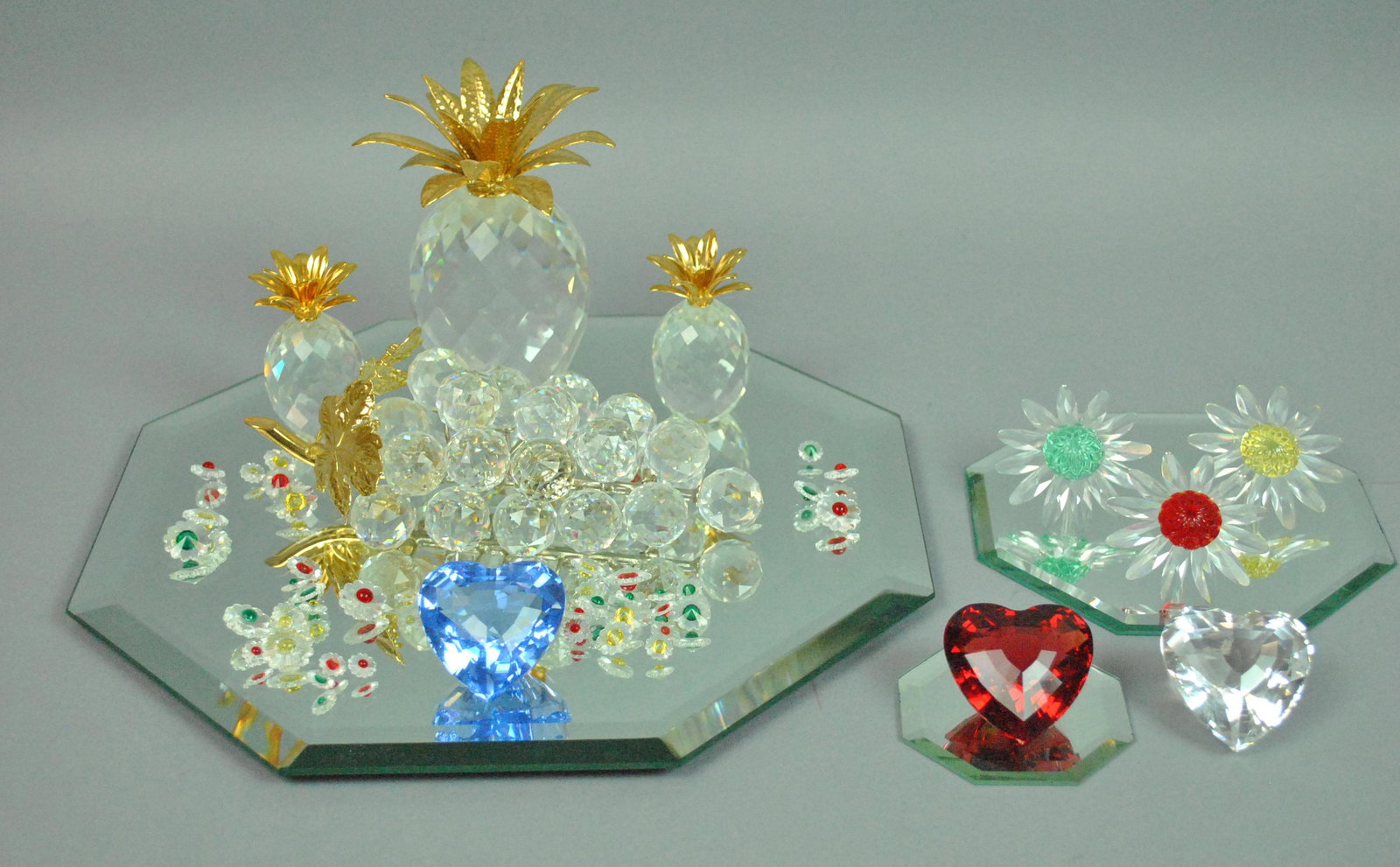 (10) SWAROVSKI FIGURALS WITH EXTRAS: (10) SWAROVSKI FIGURALS WITH EXTRAS including 3 pineapples, 3 hearts, 3 marguerite daisies, and a grape cluster, largest 6.5in., together with 35+ mini marguerite daisies and 3 octagonal display mirro