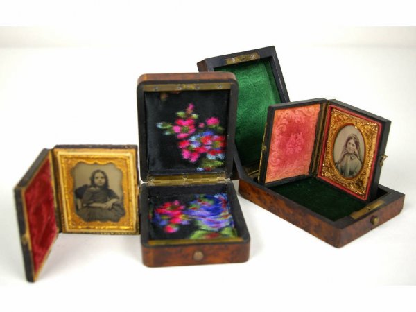 PAIR OF AMBROTYPES IN BURLWOOD BOXES: each 1/9 plate in size, one depicting a young girl with crossed hands, the other of a young woman with bonnet and neck scarf, both with tinted cheeks, housed in gutta-percha cases, each with it's own 