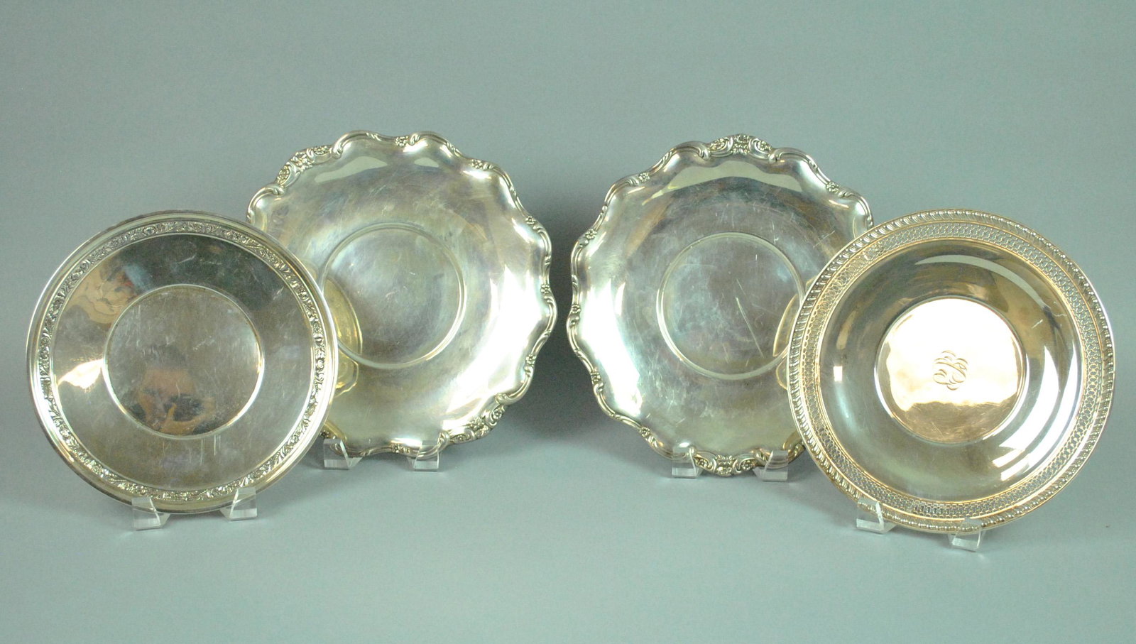 (4) STERLING UNDERPLATES: including a pair of Reed & Barton in Tara pattern, 10.25in., a pierced rim example with monogram, 9.5in., and one with floral border by Watson Co., 9in., general scratches, one with minor dent, gross 