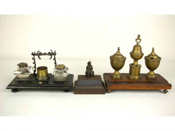 THREE VINTAGE INKSTANDS: comprising one in wood and brass, a cast iron stand with figural top (one ink well missing), and one in papier mache with glass ink wells (one with internal fracture), losses, tallest 8in. The Knoop C