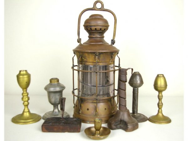 8-PIECE EARLY LIGHTING GROUP: comprising a 17" lantern by Perkins Marine Lamp Corp. (glass as is), brass and tin oil lamp bases, carved and hand-wrought candle holders, etc., losses The Knoop Collection
