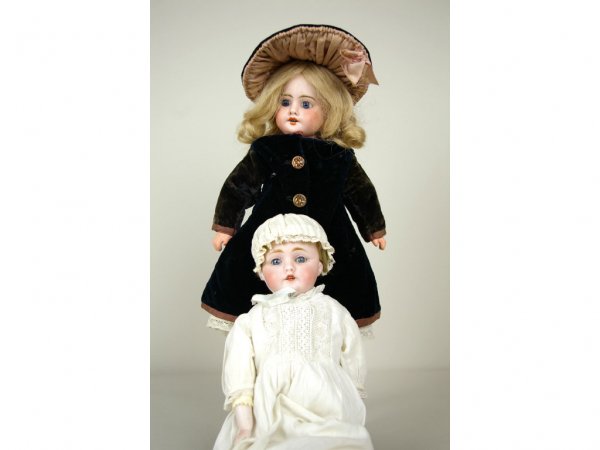 TWO BISQUE HEAD DOLLS: includes a 16" with composition body wearing a black and pink coat and hat ensemble, and a 15" with kid body and porcelain upper limbs