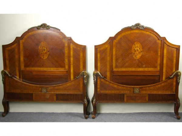 PAIR OF VINTAGE MAHOGANY INLAID TWIN BEDS: each comprising a headboard with ribbon and bow crest above a center floral medallion, a footboard with ornately scrolled trim, and side rails
