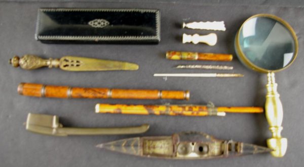 TWELVE ASSORTED DESK ARTICLES: comprising a 10" painted metal gondola ink stand with miniature treasure chest wells, a black lacquered pencil box, a Waterman's Ideal fountain pen, a bamboo letter opener in case (losses) with ivory 