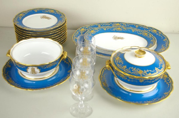 18-PIECE JULES ETIENNE PARTIAL DINNERWARE SERVICE: with ornate gilded and scrolled H monogram, including ten 9.5" plates, two 13-18" platters, two covered vegetables with underplates (one missing a cover), and four 6" fleur-de-lis cut glass stems