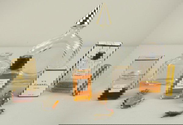 9-PIECE VANITY GROUP including a circular Guerlain: 9-PIECE VANITY GROUP including a circular Guerlain bottle, Chanel perfumes, a Guerlain bottle by Baccarat (no top), a metal scent bottle, a brass needle case, and a Revlon lipstick case THIS LOT CANNO