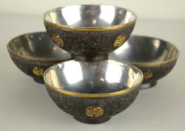 FOUR CHINESE CARVED COCONUT SHELL BOWLS: FOUR CHINESE CARVED COCONUT SHELL BOWLS each carved with four Shou symbols amongst treasures of the immortals, all silvertone metal-lined with applied goldtone metal rim, late 19th/early 20thC., 2x4.5
