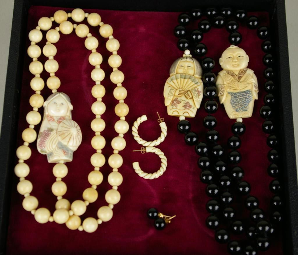 4-PIECE IVORY AND EBONY JEWELRY GROUP: comprising a 26" ivory beaded necklace with carved and polychromed signed ivory figural ornament, a 30" ebony glass beaded necklace with two carved and polychromed ivory figural ornaments, a pair of 1