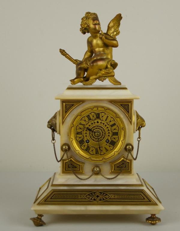 TIFFANY & CO. MARBLE AND DORE BRONZE MANTLE CLOCK: surmounted with a cherub figural seated upon a pillow and holding a torch, sides with mounted cat masks holding chain suspensions, dial signed "Tiffany & Co., New York", works signed "Tiffany & Co., 5