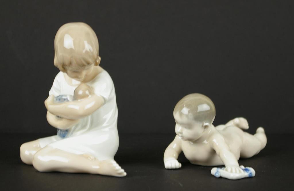 TWO ROYAL COPENHAGEN FIGURINES: one depicting a young girl cradling a doll #1938, the other a crawling baby with bootie #1739, tallest 5in.