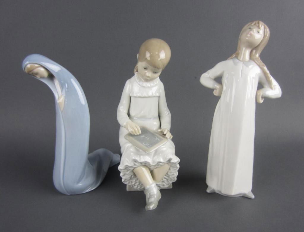 THREE LLADRO/NAO FIGURES: including a robed Lladro woman, a Lladro girl in nightgown, and a seated Nao girl with chalk board, tallest 8in.