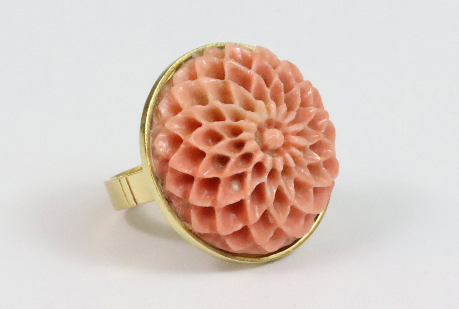 18K CARVED CORAL FLOWER MOTIF RING: 18K CARVED CORAL FLOWER MOTIF RING 1960's, comprising a finely carved central coral flower, overall diameter 24mm, in yellow gold, stamped 750, Italian provenance with COA, size 6.25, 9.6gms., Opening