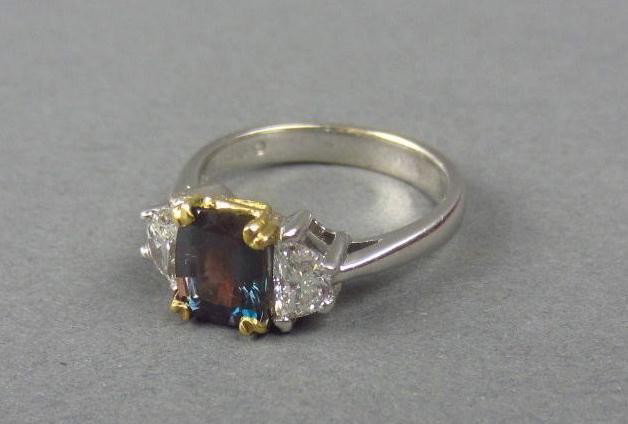 ALEXANDRITE AND DIAMOND RING, 2.19CTW: set with a cushion-cut alexandrite approx. 1.69 carats, flanked on each side by a half-moon shaped diamond approx. 0.50 carats (F-G SI1-SI2), white and yellow gold setting marked 18K, 5.1gms.
