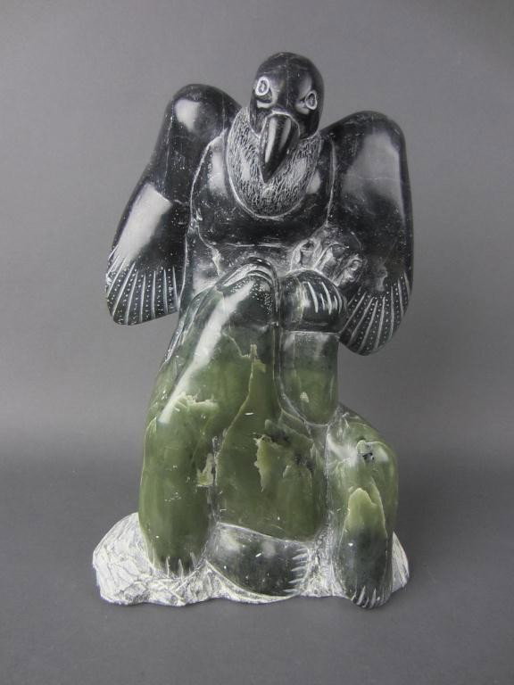 INUIT CARVED GREEN SOAPSTONE FIGURAL GROUP: depicting a bird of prey atop two seals, Canada Eskimo Art label, signed illegibly, 11x7in.