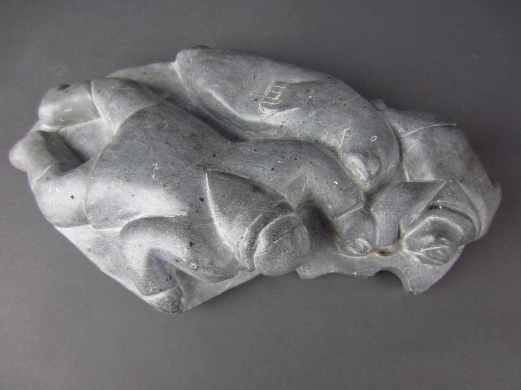 INUIT CARVED SOAPSTONE FIGURAL GROUP: depicting an adult and child prone on the ice, possibly looking for walrus, accompanied by a walrus, Canadian Eskimo Art paper label reads " Community: Sugluk/Artist: Kinasassie", numbered E.9.215, 15
