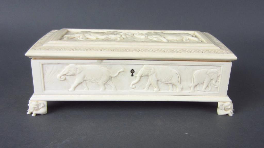 ASIAN ELEPHANT IVORY CARVED HINGED BOX: the lid panel depicts two bull water buffaloes fighting, the four side panels depict elephants, lions and hares, crouched elephant feet, minor dry cracks, with key, 2x7x4in. NO INTERNATIONAL SHIPPING.