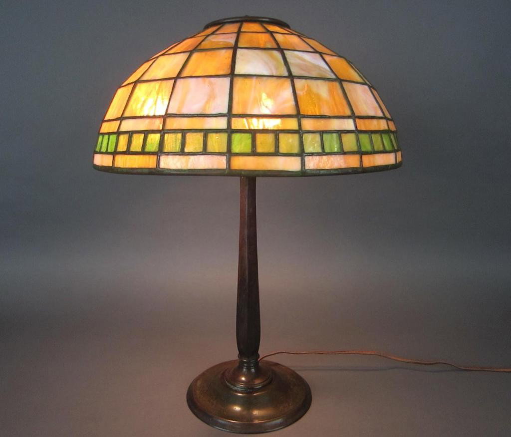 TIFFANY STUDIOS LEADED GLASS AND BRONZE LAMP: the shade with yellow and green ground in geometric pattern, stamped Tiffany Studios New York, base stamped Tiffany Studios New York 538, diameter of shade 16in., base height 21.5in.