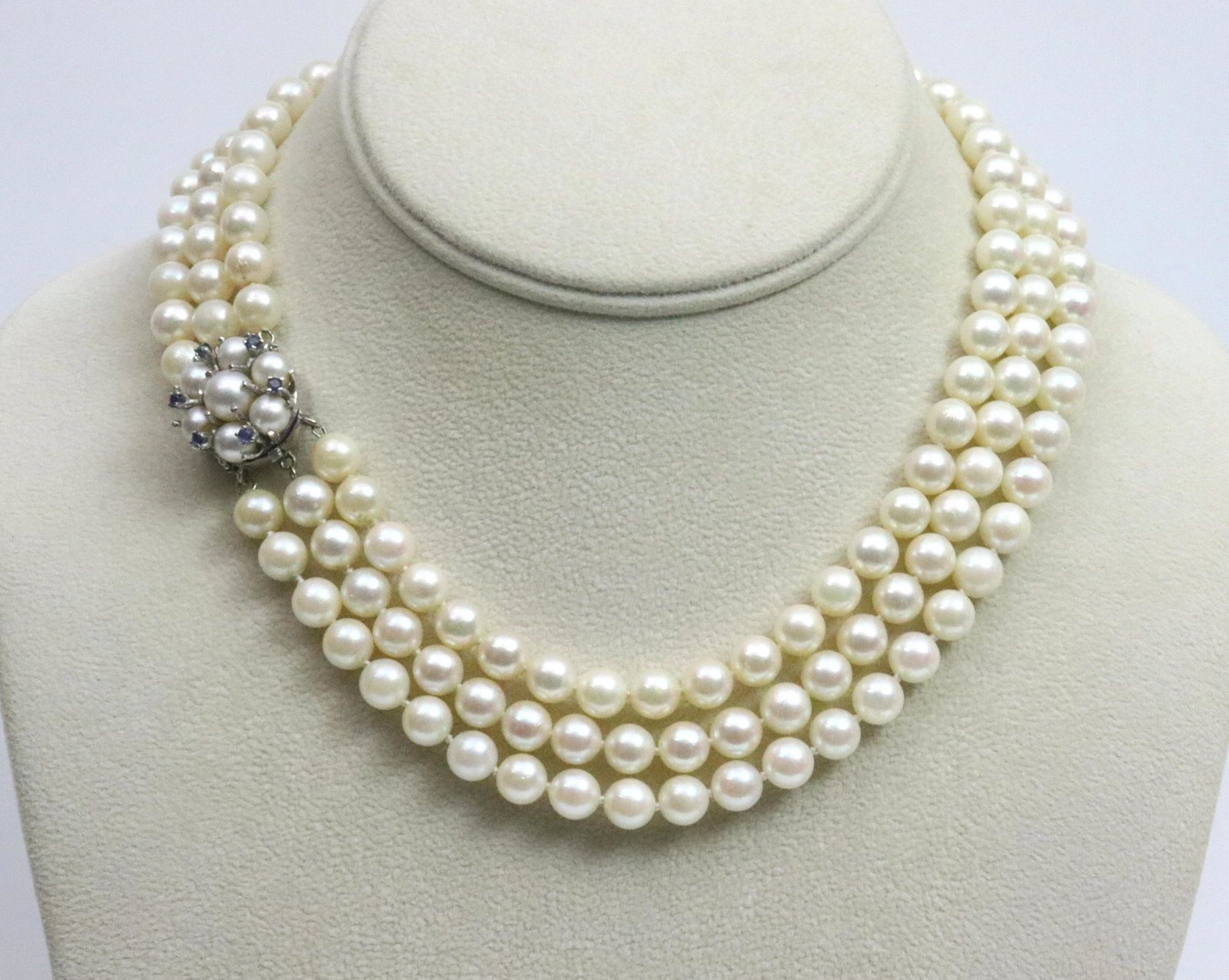 14K 3-STRAND CHOKER LENGTH PEARL NECKLACE: comprising (7mm) cultured pearls, the pearl clasp accented with 6 round sapphires approx. 0.24 carat, in white gold, stamped 14K, safety catch, overall good condition, some typical dimples and blemish