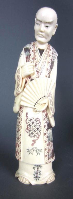 CARVED IVORY AND POLYCHROME SCRIMSHAWED FIGURE: of a gent holding open fan, sandaled feet and heavily decorated robes, signed on base, 9.5in. NO INTERNATIONAL SHIPPING.