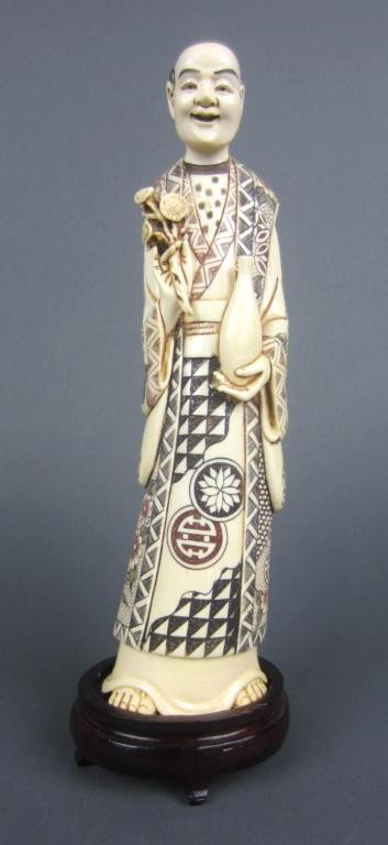 CARVED IVORY AND POLYCHROME SCRIMSHAWED FIGURE: of a gent holding flowers and an empty vase, sandaled feet and heavily decorated robes, minor drying cracks, signed on base, 10in. NO INTERNATIONAL SHIPPING.