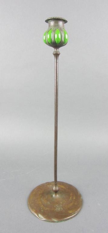 TIFFANY STUDIOS BRONZE AND GLASS CANDLESTICK: the bulbous cup with blown-out green glass panels (one panel with punctured glass, minor flakes to glass rim), beaded bobeche insert, signed Tiffany Studios New York 30054, monogrammed, 17in. Note: Th