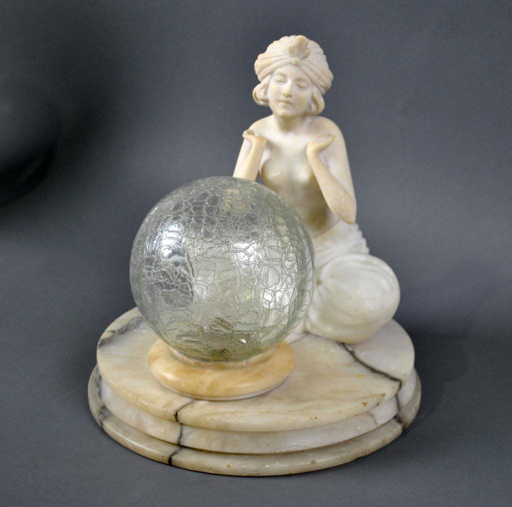 ART DECO FIGURAL ALABASTER TABLE LAMP: depicting a crossed legged, partial nude in Arabesque garb and feathered headscarf, crackle glass globe, on a round base, 13x12in.