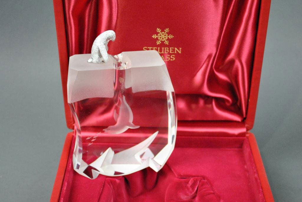 STEUBEN SCULPTURE - ICE PENGUIN: designed by James Houston, having an etched glass ice cap above a colorless glass body of water, a silvered metal penguin peering through a crack revealing a seal chasing fish, 6in., in presentation b