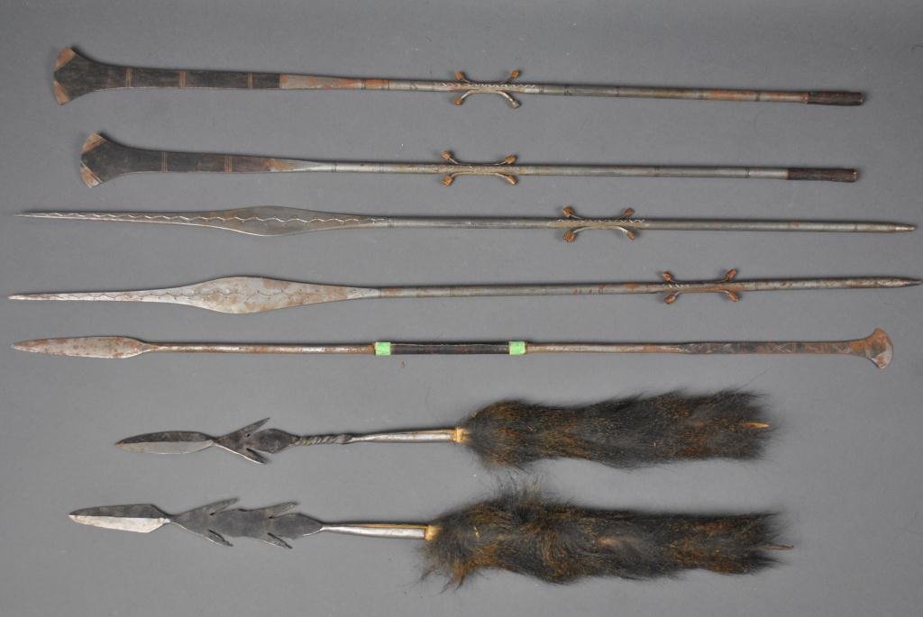 SEVEN ETHNOGRAPHIC METALWARE ARTICLES: including spear points and shafts, two with feathers (likely cassowary), some rust and pitting, longest section 32in.