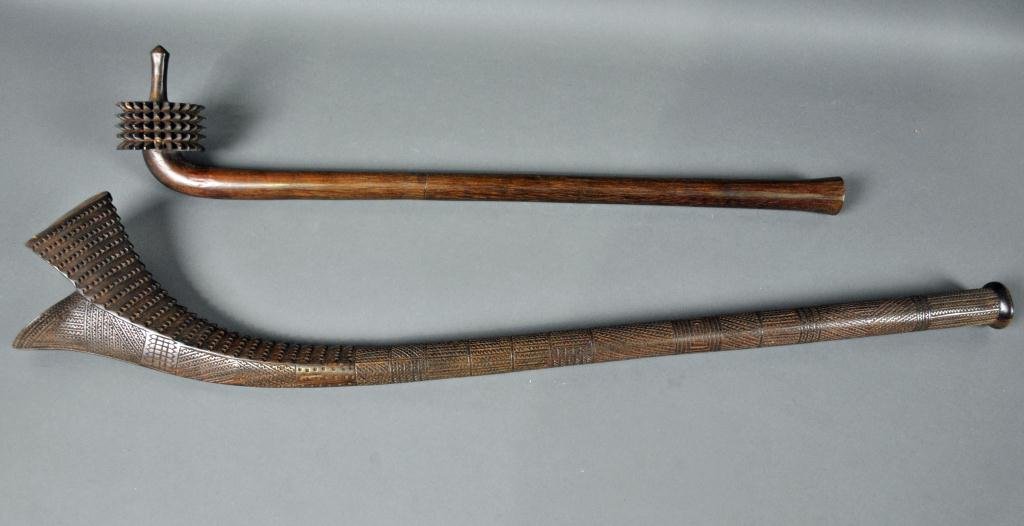TWO CARVED WOOD CLUBS - FIJI: includes a gunstock club with heavy saw-tooth carving on head and chip-carved shaft, 40in., and a pineapple club with unadorned shaft, missing one tooth, one glued, 32in.