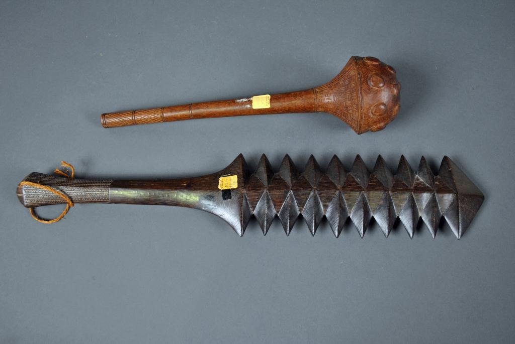 TWO CARVED WOOD CLUBS - FIJI: one a throwing club with partial chip-carved handle and underside of head, the other a saw-tooth club with chip-carved handle, longest 23in.