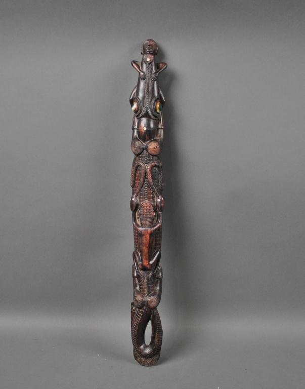 CROCODILE TOTEM CARVING - PROBABLY SEPIK RIVER: depicted with zoomorphic figure, snakes and a native in its mouth, mother of pearl accents and unusual porcelain or shell eyes, 24in.