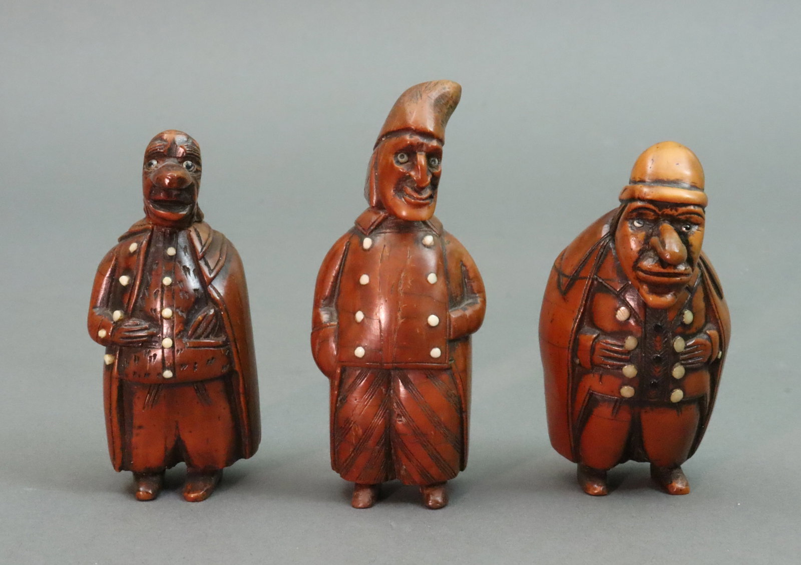 (3) CARVED COQUILLA NUT CHARACTERS: all with exaggerated features in overcoats with bone buttons, 2 with hats, one with glass eyes, the others with bone eyes, all with hinged snuff compartments, purchased Rogers de Rin, London, 1990's, 