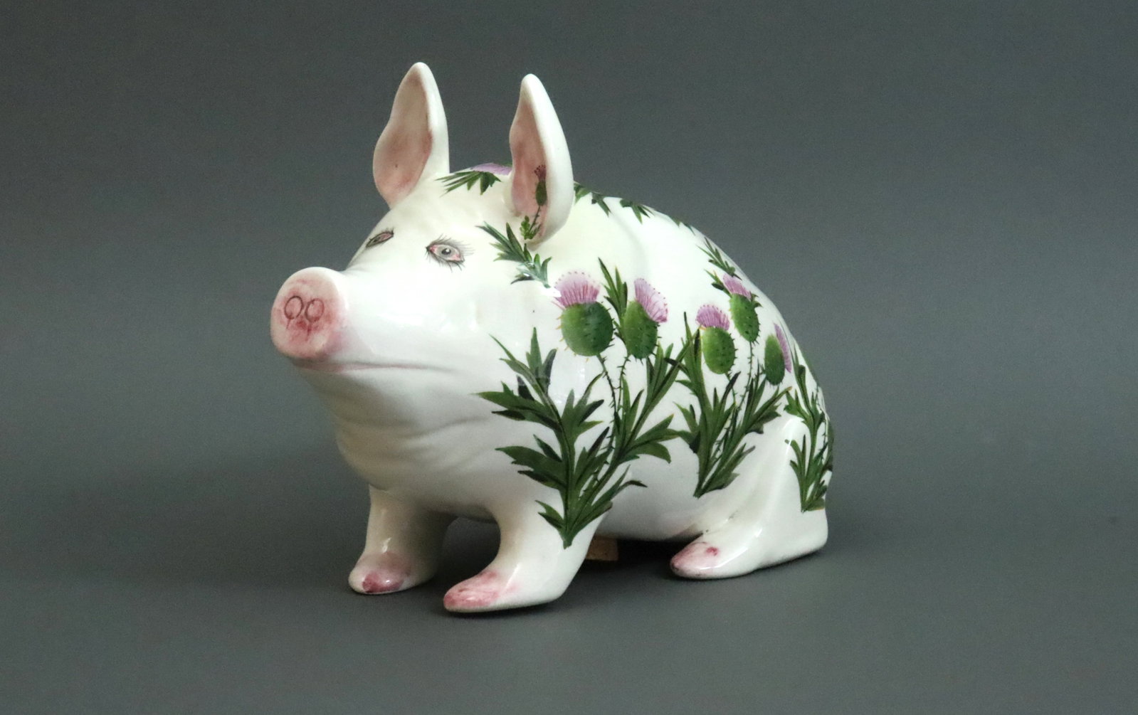 MEDIUM WEMYSS FOR PLICHTA THISTLE MONEYBANK PIG: painted in blooming thistles, stamped 'Plichta London England', bearing sticker of Rogers de Rin, London, purchased 1997, allover light crazing, UV light reveals a professional restoration to left sid