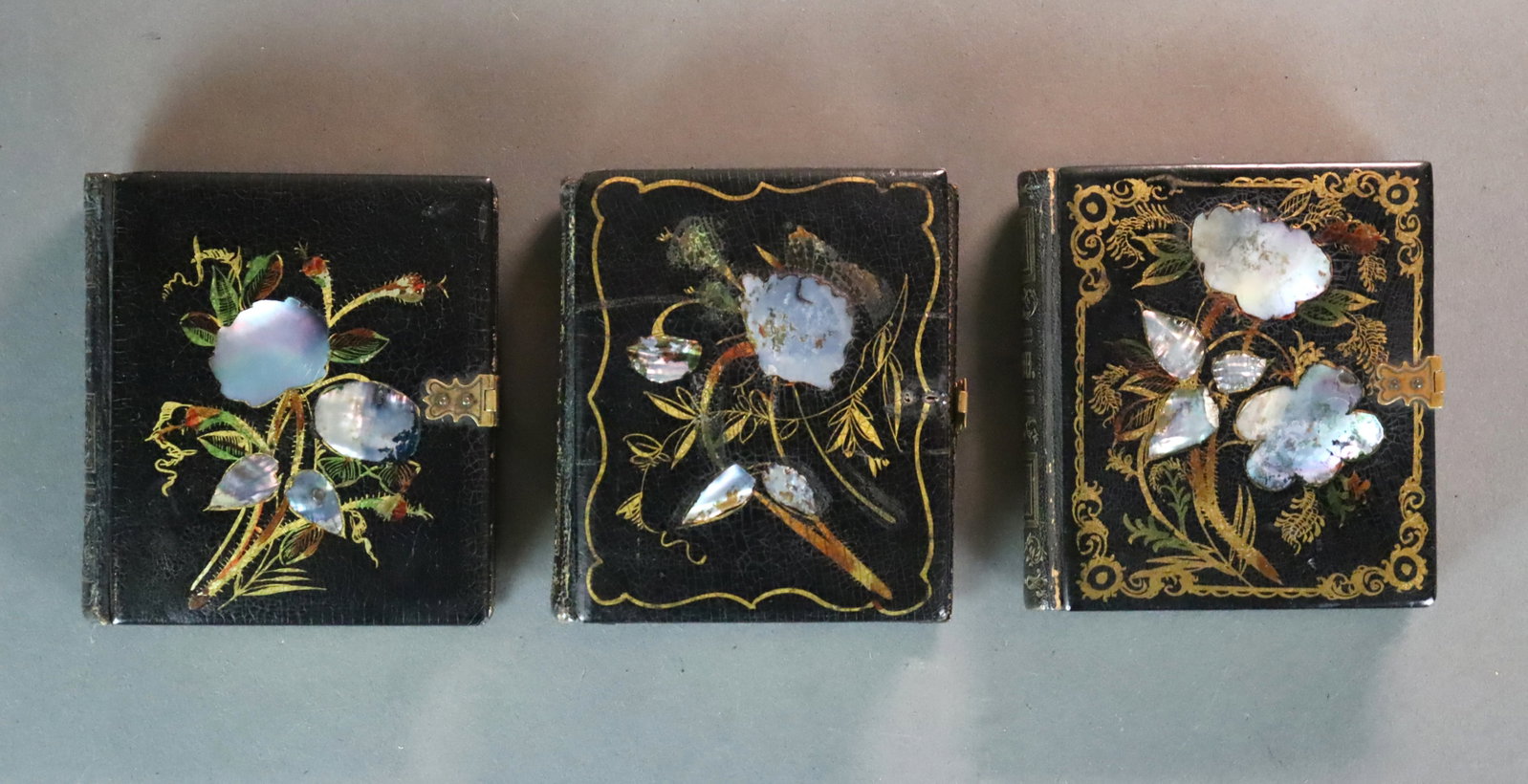 (3) JAPANNED DOUBLE BOOK-FORM CASES WITH 6 IMAGES: Each case in black lacquer with mother-of-pearl inlay housing a double sided daguerreotype portrait of a husband and wife, cases with wear and some losses (one missing top hardware closure, bottom har