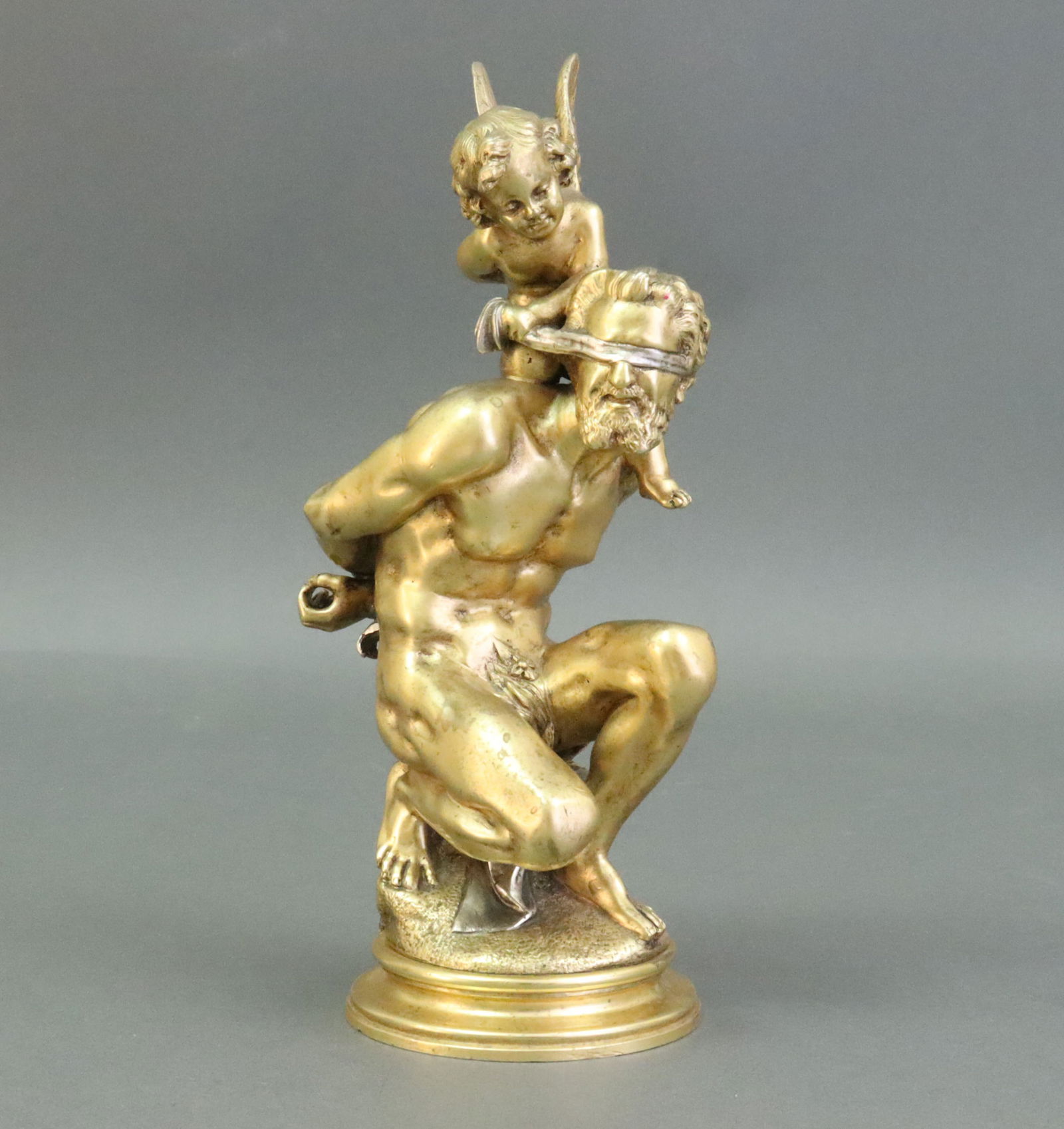 JEAN BARNABE AMY (French, 1839-1907): a gilt and silvered cabinet bronze depicting a cherub and partially nude blindfolded man seated on a stump, signed 'Amy' on stump verso, raised on a gilt bronze plinth, a couple minor dings to base ed