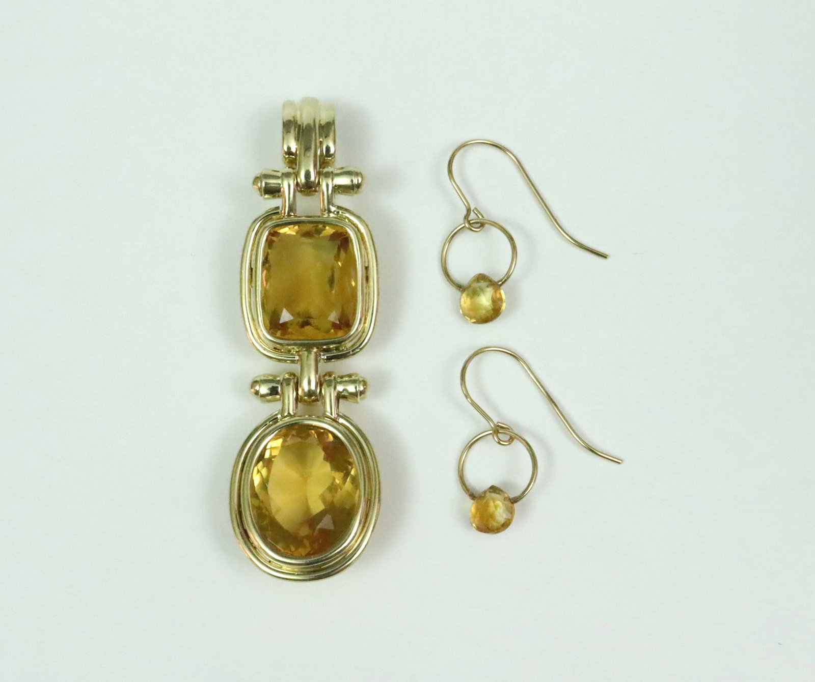 14K LARGE CITRINE PENDANT AND A PAIR OF EARRINGS: the pendant set with 2 faceted citrine stones, one a rectangular cut approx. 9.71ct (14.5x12x8.1mm), the other an oval cut approx. 9.78ct (16.5x13x8.6mm), bale stamped 14K, and with illegible maker's 