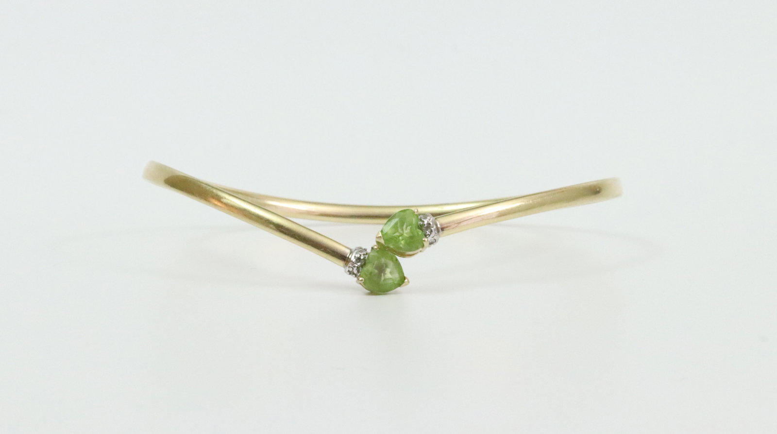 14K PERIDOT & DIAMOND BYPASS FLEX BANGLE: set with heart shape peridot terminals each approx. 6x6mm, accented with 6 melee diamonds, interior diameter 7in., 4.6gms., Opening Bid $200