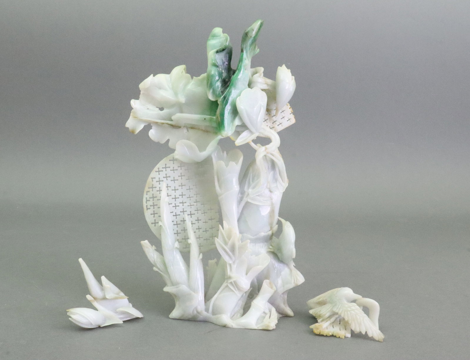 AS-IS CHINESE JADE BAMBOO CARVING: in white with bright green inclusions carved into leaves, depicting bamboo shoots and lotus buds fronting a pierced disk, moderate breakage and loss including pierced disc, 2 birds broken off but pres