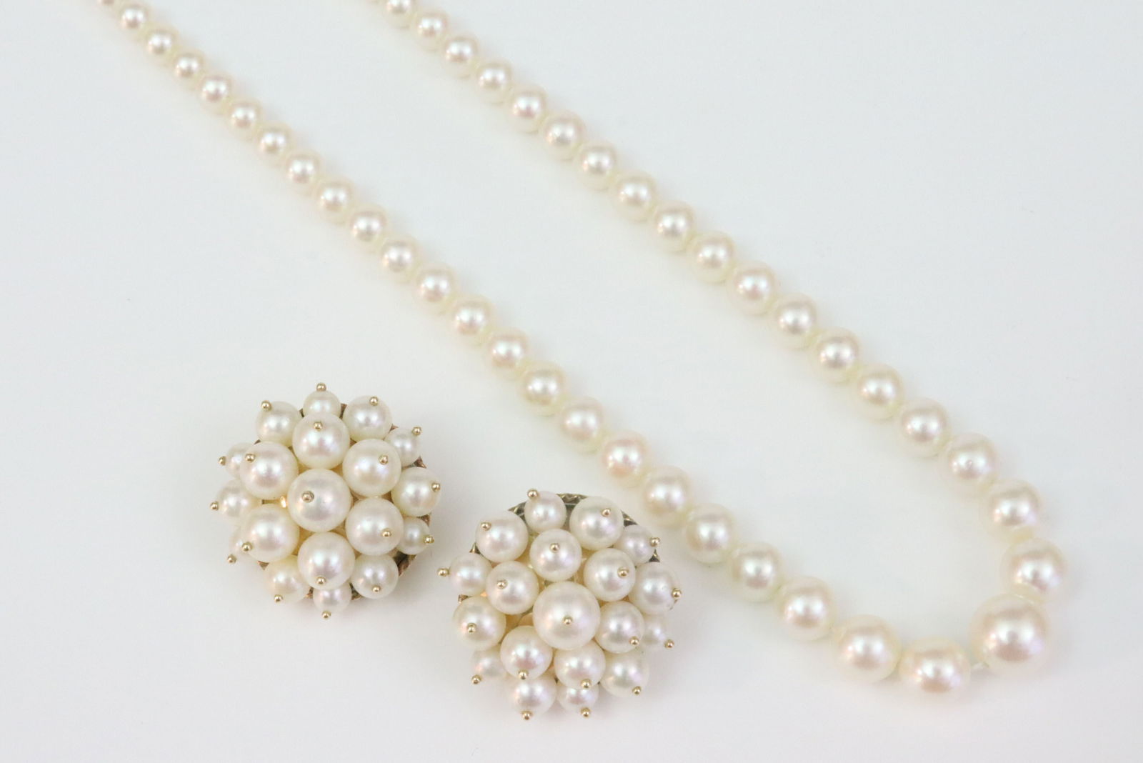 14K CULTURED PEARL NECKLACE AND A PAIR OF EARRINGS: the necklace comprising graduated (3-7mm) pearls (some minor visible string toward clasp end, 14K fish hook clasp not working), 18in., together with a pair of 19mm pearl clip-on button earrings (one c