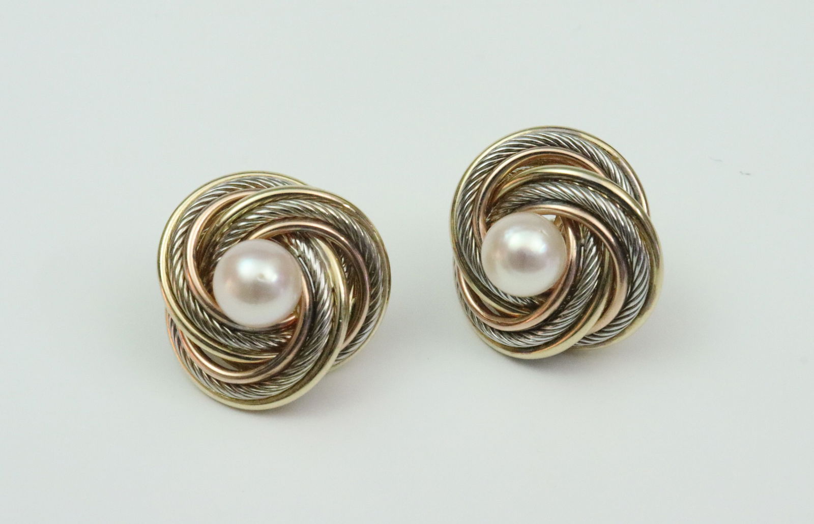 PAIR 14K PEARL BUTTON EARRINGS: each set with a 7mm cultured pearl within a bicolor swirl setting, overall approx. 20mm, post and backs stamped 14K, 6gms., Opening Bid $200