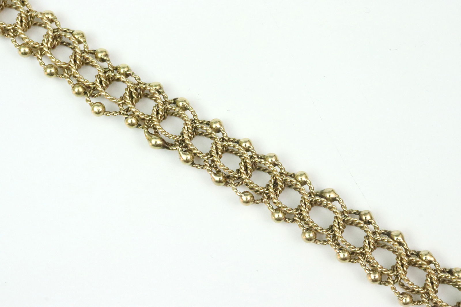 14K PARALLEL LINK BRACELET: with bead trim, has a touch of flexibility, width 13mm, length 7.5in., some asymmetrical links and beads, a couple minor spots of darkened gold, stamped 14K, safety catch, 26.8gms., Opening Bid $1600