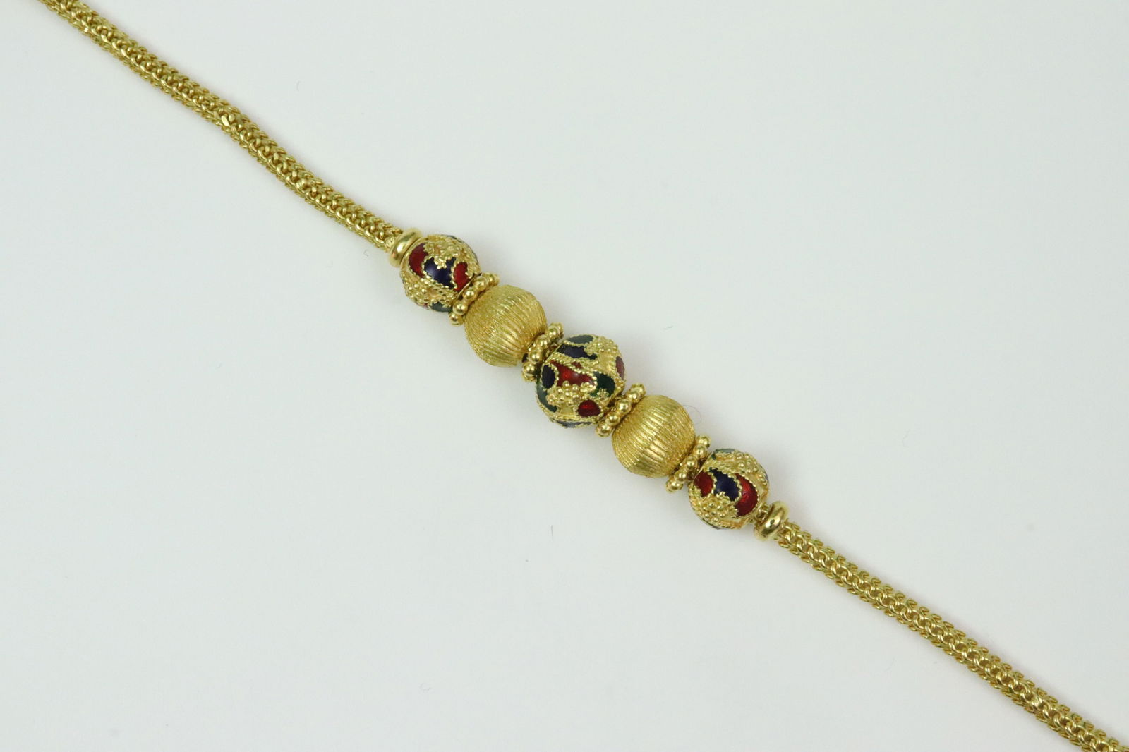 22K MESH LINK & ENAMEL BRACELET: purchased in Thailand c.2003, with enameled accented beads and cuffs, largest bead 8.5mm, in yellow gold, illegible multi-character mark, tests 22K, S-hook clasp, length 6.5in., 15.2gms., Opening Bid