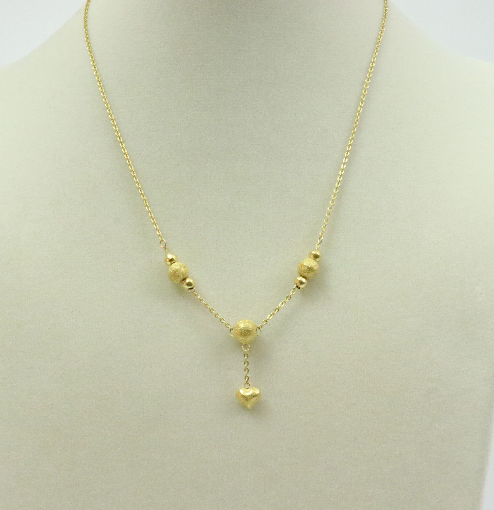 22K BALL & HEART DANGLE NECKLACE: purchased in Thailand c.2003, comprising textured and polished balls and beads with dangling heart, largest ball 7mm, cable link chain, in yellow gold, tests 22K, S-hook clasp, length 16.5in., 7gms.,