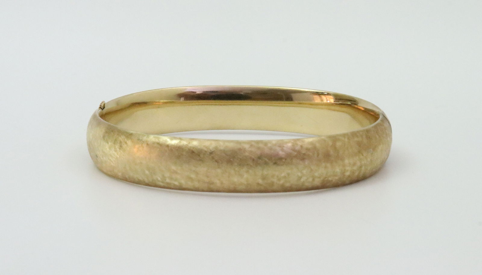 14K SLIDE HINGED BANGLE BRACELET: in yellow brushed gold, stamped 14KT, width 10mm, inner circumference 6.5in., 17.4gms., Opening Bid $1000