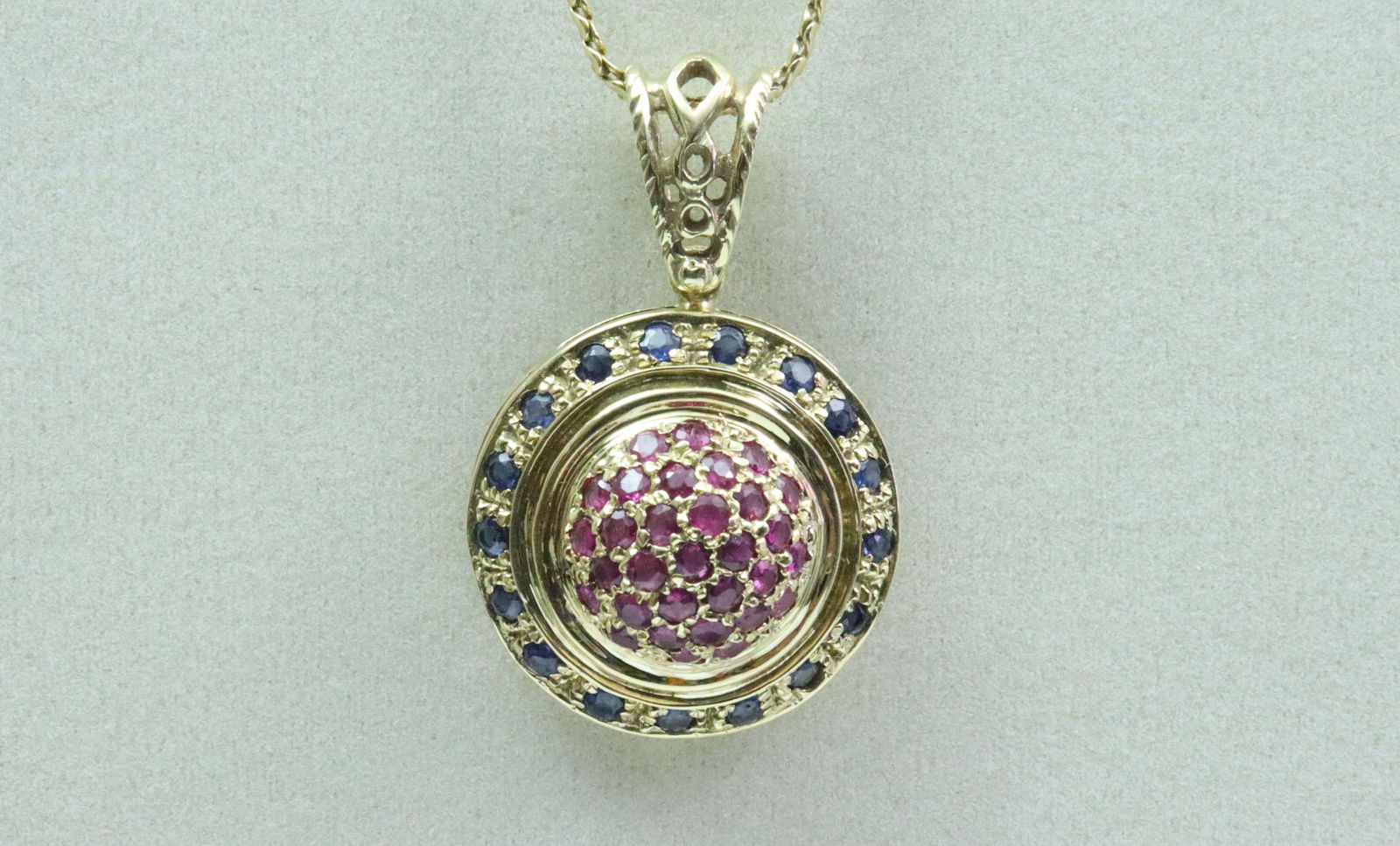 18K RUBY & SAPPHIRE BOULE STYLE PENDANT ON CHAIN: the pendant set with 48 round cut rubies and sapphires approx. 1.80ctw, overall diameter 22mm, length including filigree bale 33mm, tests 18K, 9gms., on 21" serpentine neckchain stamped '750 UNO
