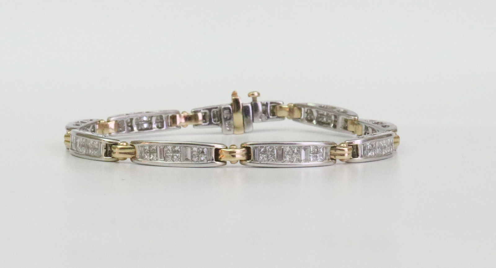 14K DIAMOND LINK BICOLOR BRACELET: designed in slightly domed links comprising 144 square and baguette diamonds approx. 5.40ctw, in white and yellow gold, stamped '14K JX', width 4.5mm, length 7.2in., fold-under safety, 16.3gms.,