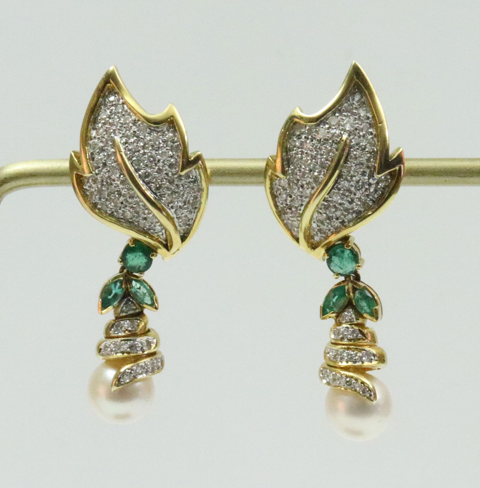 PAIR 18K DIAMOND, EMERALD & PEARL DROP EARRINGS: designed in leaf form, each leaf encrusted with pave-set melee diamonds suspending a (7mm) pearl, total diamond weight for the pair 0.70ctw., further accented with 6 melee emeralds, in yellow gold,