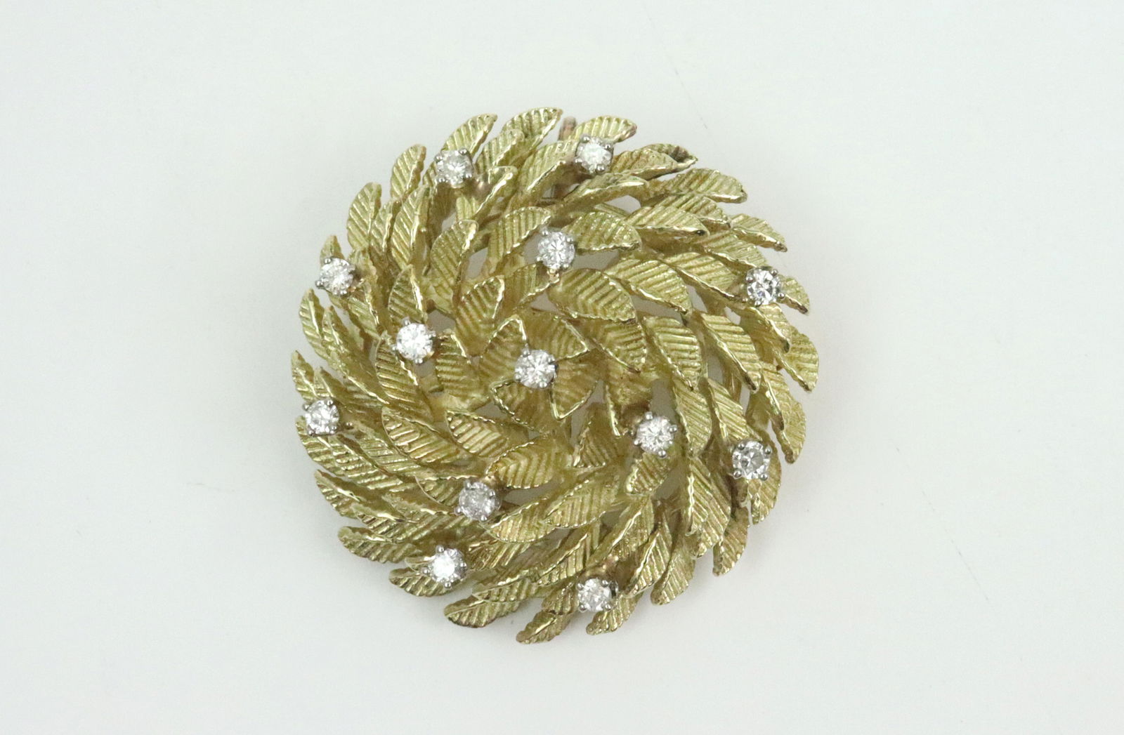 14K DIAMOND BOULE STYLE BROOCH: in swirled leaf design accented with 13 round diamonds approx. 0.60ctw, in yellow textured gold, tests 14K (non-gold likely added bale, pin stem with bend, some tarnish), diameter 1.3in., 19gms., Open